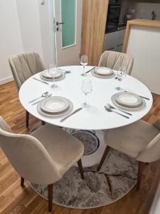 une table blanche avec des chaises, des assiettes et des verres dans l'établissement Apartman Valentina, à Trebinje