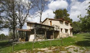 een oud huis in een veld met een hek ervoor bij La Cerquilla in Segovia