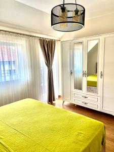 a bedroom with a green bed and a large window at M&M Center Apartment with free parking in Plovdiv
