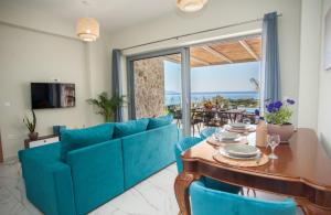 sala de estar con sofá azul, mesa y sillas en Natural Stone Villas Kefalonia en Trapezaki