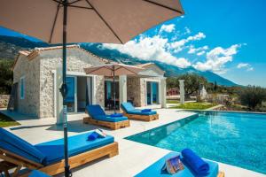 Villa con piscina con sillas y sombrilla en Natural Stone Villas Kefalonia en Trapezaki