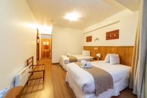 a hotel room with three beds and a television at Hotel Qalasaya in Puno