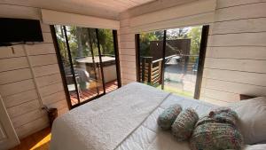 um quarto com uma cama e uma grande janela em Cabaña del Bosque em Pichilemu