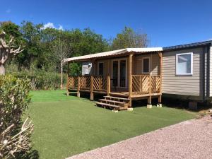 a small cabin with a porch and a grass yard at Azur in Fréjus