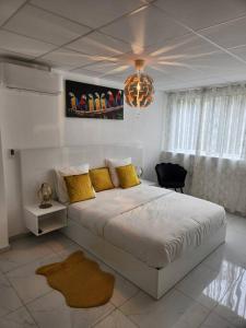 1 dormitorio blanco con 1 cama grande con almohadas amarillas en Hello-Guyane, Marina 2, Studio Prestige 5 étoiles, en Saint-Laurent-du-Maroni
