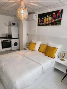 1 dormitorio blanco con 1 cama grande con almohadas amarillas en Hello-Guyane, Marina 2, Studio Prestige 5 étoiles, en Saint-Laurent-du-Maroni