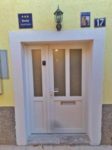 a white door on a yellow building at Holiday Place Veli Dvor - vacation house with private garden in old town Punat in Punat