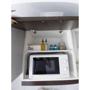 a microwave in a shelf in a kitchen at Shanti Alojamiento Monoambiente y Departamento in Mendoza