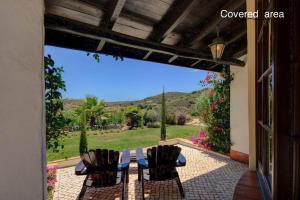 une terrasse couverte avec une table et des chaises. dans l'établissement Quinta Casa May, à Budens