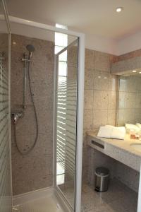 a bathroom with a shower with a glass door at Hôtel Les Trois Roses, Meylan Grenoble The Originals Boutique in Meylan