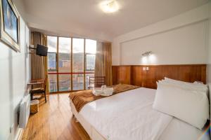 1 dormitorio con cama blanca y ventana grande en Hotel Qalasaya en Puno