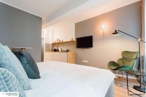 Schlafzimmer mit einem Bett, einem TV und einem Stuhl in der Unterkunft City-Studio mit Boxspring-Bett und Küche in Münster