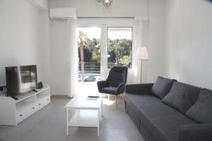 sala de estar con sofá, TV y silla en Stylish Apartment in City Center, en Heraclión