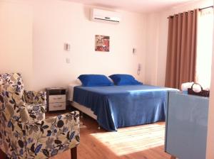 a bedroom with a bed with blue sheets and a chair at The Hyperion Boutique Hotel in Florianópolis +63 photos