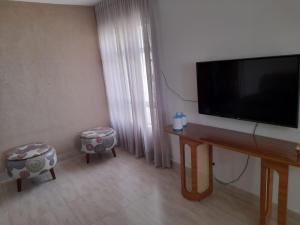 a living room with a flat screen tv and two chairs at Apartamento Aconchegante SETOR OESTE in Goiânia