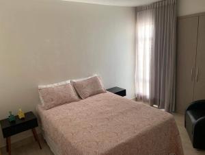 a bedroom with a bed and a chair and a window at Apartamento Aconchegante SETOR OESTE in Goiânia