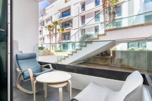 balkon z 2 krzesłami, stołem i schodami w obiekcie Luxury apartment Anfaplace, close to the beach w mieście Casablanca