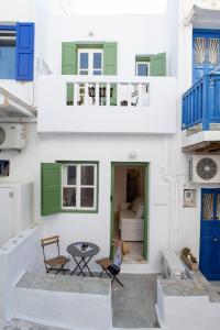 un edificio blanco con puertas azules y verdes y una mesa en MYKONOS HOUSE Eternity maisonette , Mykonos Town en Mykonos ciudad