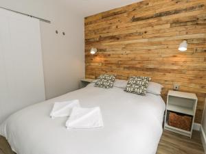a bedroom with a white bed with a wooden wall at Peris Lodge in Caernarfon