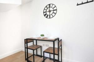 a table with two stools and a clock on a wall at Central Buckingham Apartment #1 with Free Parking, Pool Table, Fast Wifi and Smart TV with Netflix by Yoko Property in Buckingham