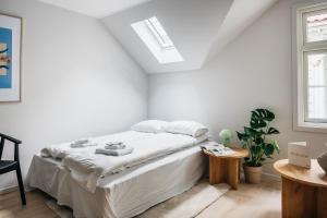 a white bedroom with a bed and a window at Stay Fløyen in Bergen