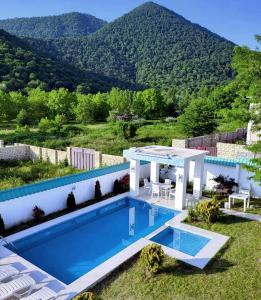 una piscina con pérgola y montañas de fondo en Qafqaz Manor Grafana, en Gabala