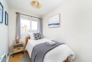 ein weißes Schlafzimmer mit einem Bett und einem Fenster in der Unterkunft Homely and Stylish Bermondsey Apartment with Parking in London