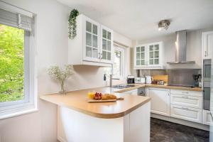 een keuken met witte kasten en een tafel met fruit erop bij Homely and Stylish Bermondsey Apartment with Parking in Londen
