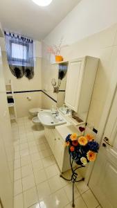 a bathroom with a sink and a toilet and a vase of flowers at Fontecorona Bed and Breakfast in Serra San Quirico
