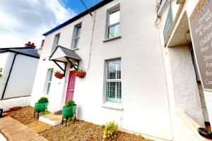a white house with green chairs in front of it at CROYDE BRIAR HOUSE 4 Bedrooms in Croyde