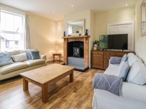 ein Wohnzimmer mit einem Sofa, einem TV und einem Tisch in der Unterkunft The Mill House in Carrog