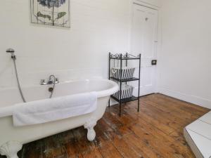 eine weiße Badewanne im Bad mit Holzboden in der Unterkunft The Mill House in Carrog