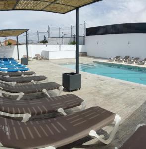 a group of lounge chairs next to a swimming pool at A 15 minutos Granada piscina jacuzzi barbacoa in Güevéjar