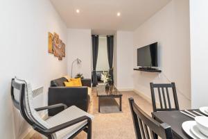 Luxe Apartment Central Bradford في برادفورد: غرفة معيشة مع أريكة وطاولة مع كراسي