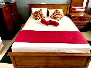 ジャフナにあるYal's Town Innのベッド1台(上に赤い枕2つ付)