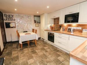 a kitchen with a table and a kitchen with white cabinets at Piggy Bank Cottage in Sedbergh