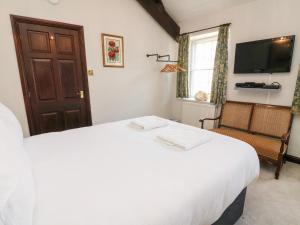 a bedroom with a large white bed and a window at Piggy Bank Cottage in Sedbergh