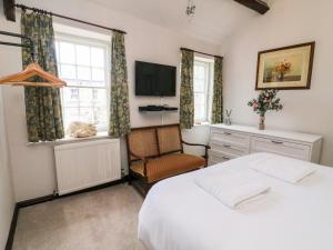 a bedroom with a bed and a tv and a chair at Piggy Bank Cottage in Sedbergh