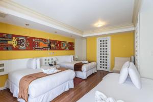 two beds in a hotel room with yellow walls at Hotel Qalasaya in Puno