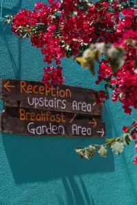 a wooden sign on a wall with red flowers at Natural Mystic Hostel in Costa da Caparica