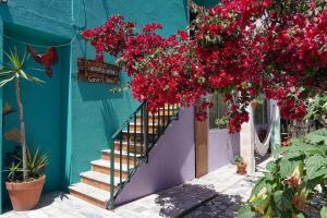 a blue building with flowers hanging from a staircase at Natural Mystic Hostel in Costa da Caparica