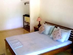 1 dormitorio con 1 cama grande con sábanas y almohadas blancas en Le Grand Meaulnes en Habarana
