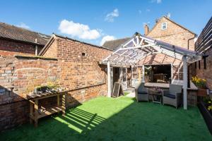 a garden with a greenhouse in a brick building at Cheshire Boutique Bathhouse in Nantwich