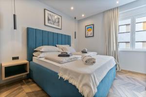 a bed with a blue headboard in a bedroom at West Coast Deluxe Rooms - Vacation Rental in Split