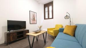 sala de estar con sofá azul y sillas amarillas en Alojamiento Los naranjos Piscina y Parking Gratuito, en Jaén