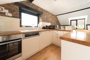 een keuken met witte kasten en een bakstenen muur bij Swallow Cottage at Robin Hill 4 in Bideford