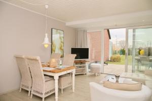 un soggiorno con tavolo, sedie e televisione di Haus Moin Moin a Grömitz