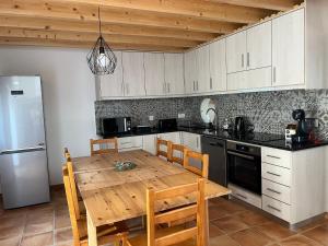 a kitchen with a wooden table and a refrigerator at Quinta do Carvalho Cerquinho in Louriceiras de Baixo