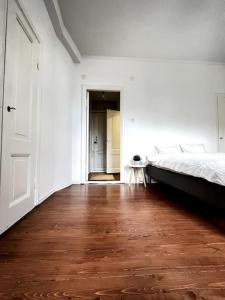 a white room with a bed and a wooden floor at Studio Mansku in Helsinki