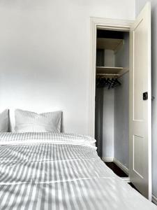 a white bed in a room with an open door at Studio Mansku in Helsinki
